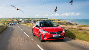 bright red corsa driving along a coast