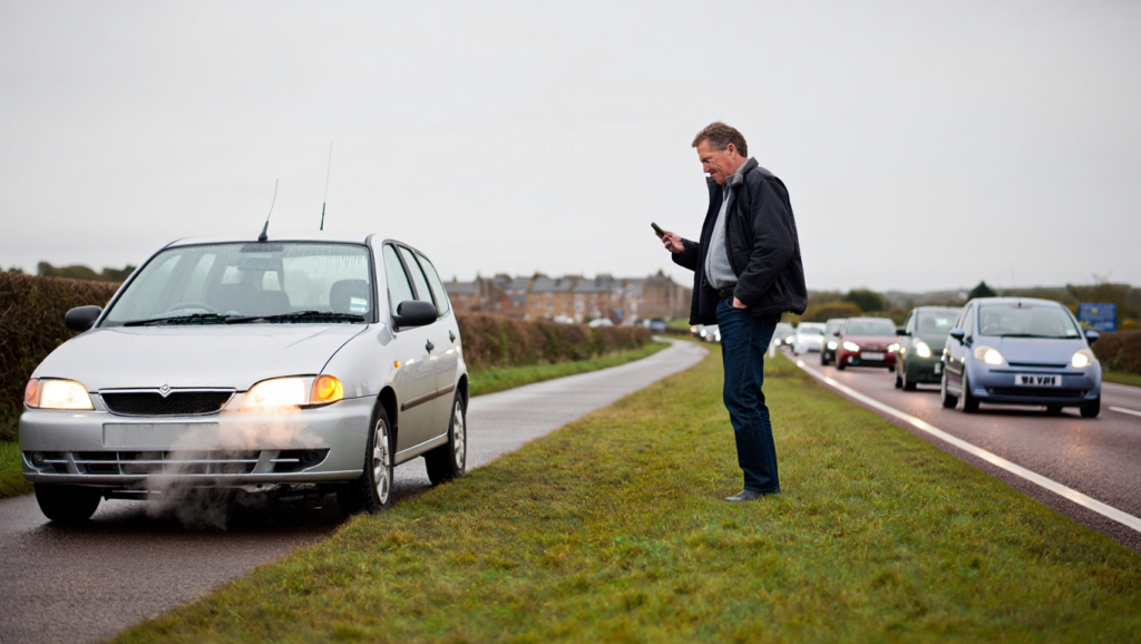 Car overheating in traffic with steam visible while waiting for recovery.