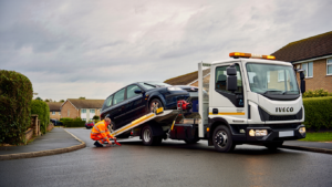 Recovery driver loading a non starting car onto a flatbed with skates in Sittingbourne, Kent.